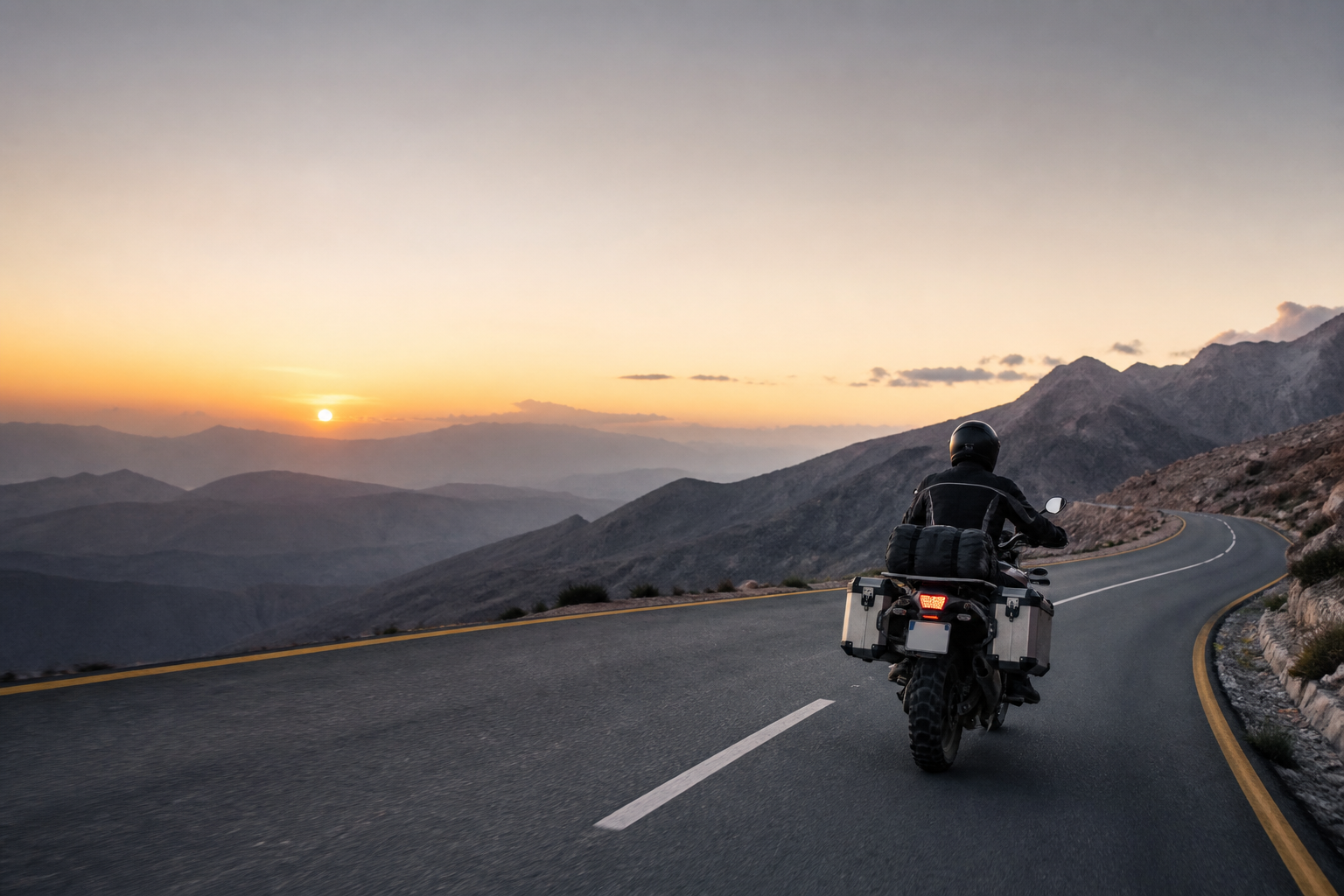 A motorcycle rider on a mountain road at dawn